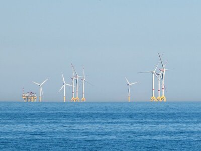 Mehrere Windkrafträder auf offener See mit einer Versorgungstation